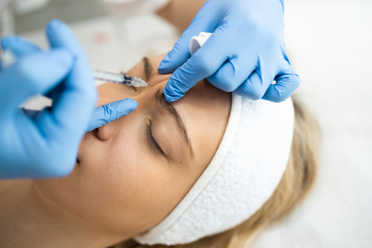 Beautician makes botox injections in the area between the eyebrows. Anti aging procedure