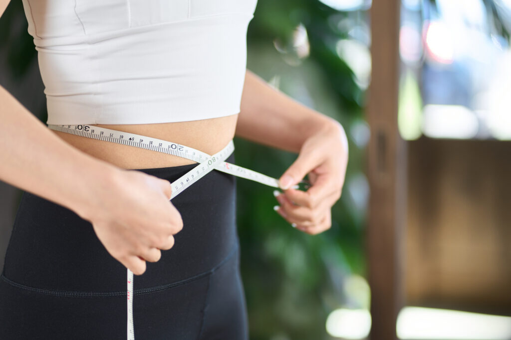 Women measuring waist after weight loss