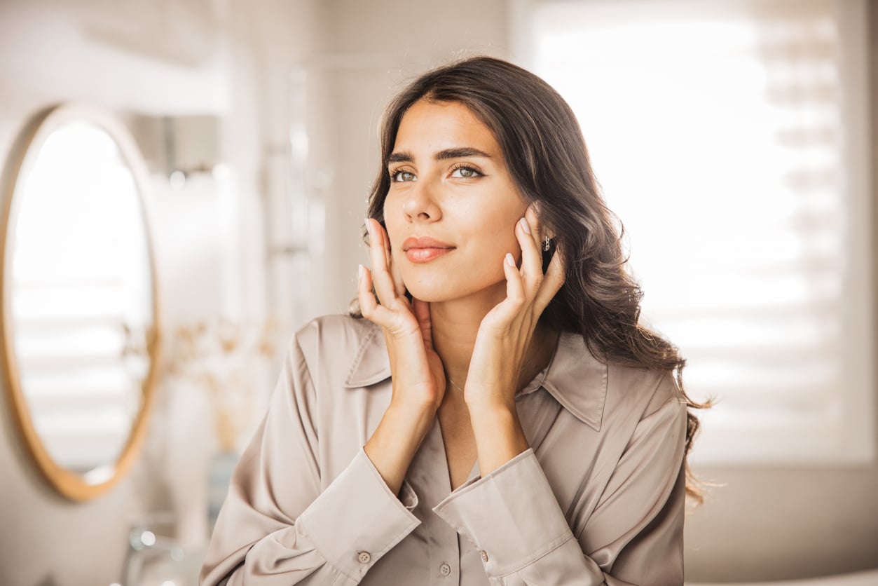 Portrait of young woman with smooth cheeks looking at mirror